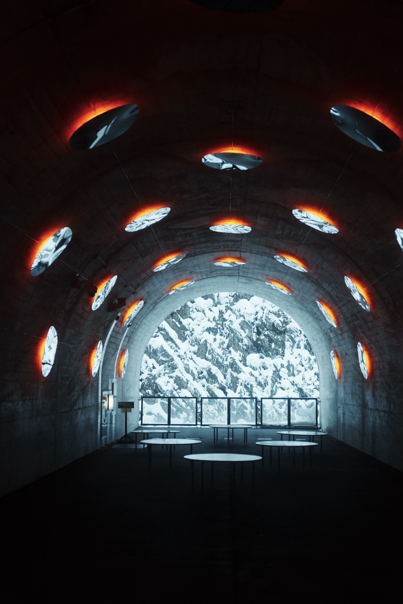 Circular illuminated tunnel opening onto a snowy forest