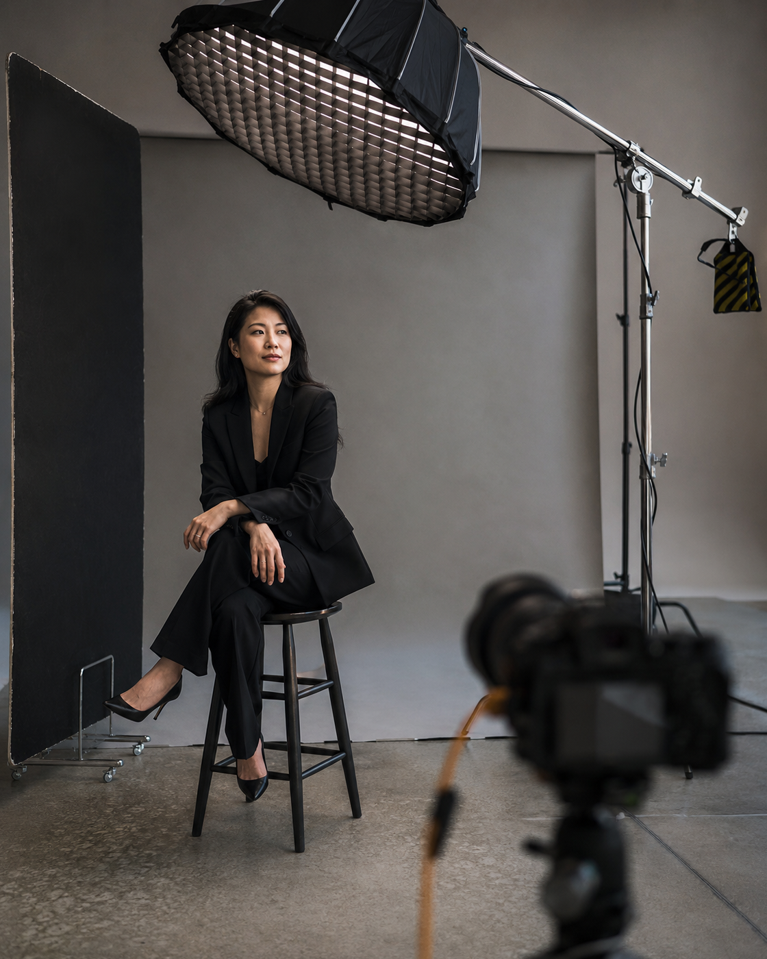 Asian founder seated beneath a large overhead octagonal softbox on a professional portrait set